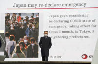 FILE - In this Jan. 5, 2021, file photo, a man wearing a mask against the spread of the coronavirus walks in front of a screen showing the news on possible Japan's State of Emergency in Tokyo. Opposition to the Tokyo Olympics is growing with calls for a cancellation as virus cases rise in Japan. The International Olympic Committee and local organizers have already said another postponement is impossible, leaving cancellation, or going ahead, as the only options. (AP Photo/Eugene Hoshiko, File)