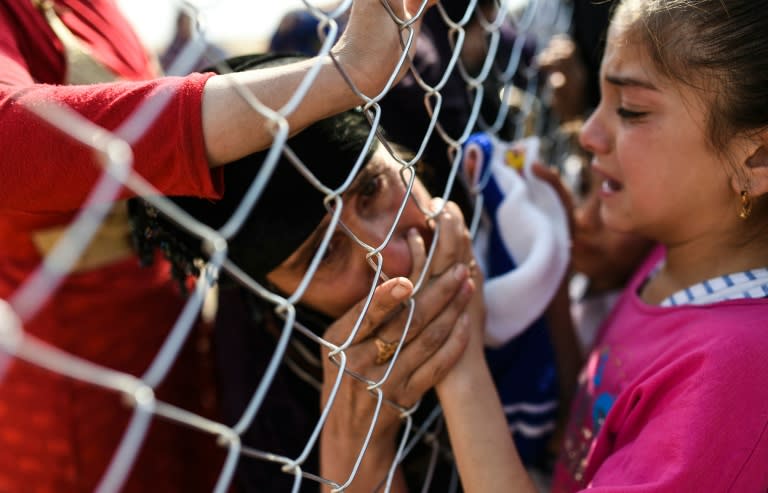 Newly-reunited relatives clutched hands through the links of the fence at a camp for the displaced in Khazir