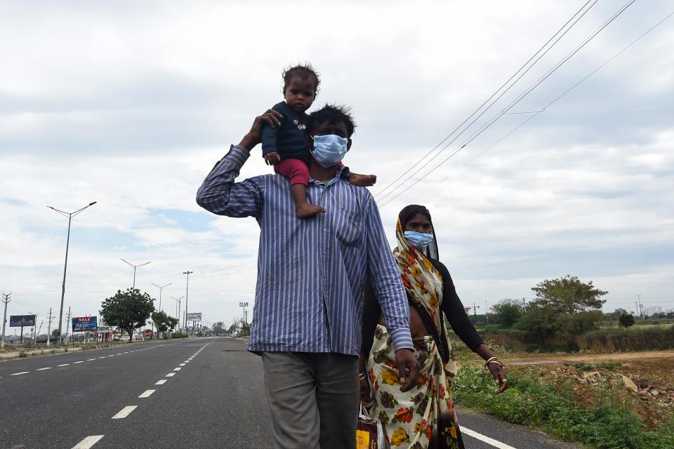 A migrant worker carries a baby on his shoulder as he along with others walks on a highway towards Uttar Pradesh during a government-imposed nationwide lockdown as a preventive measure against the COVID-19 coronavirus, in Faridabad on March 27, 2020. (Photo by Money SHARMA / AFP) (Photo by MONEY SHARMA/AFP via Getty Images)