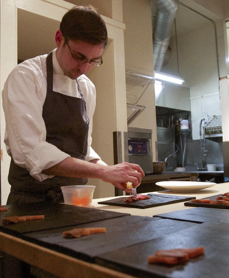 In this Jan. 19, 2013 photo, Chef Justin Woodward of the restaurant Castagna builds a dish of cherry-smoked steelhead, blood orange, endive, dried chiles served on a slate in Portland, Ore. "We're kind of the Wild West," he says. "We don't have a Michelin Guide. We don't have The New York Times breathing down our neck. We can basically do whatever we want." (AP Photo/The Oregonian, Doug Beghtel)