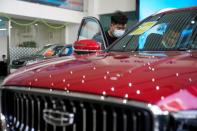 People look at a Geely vehicle at a car dealership in Shanghai