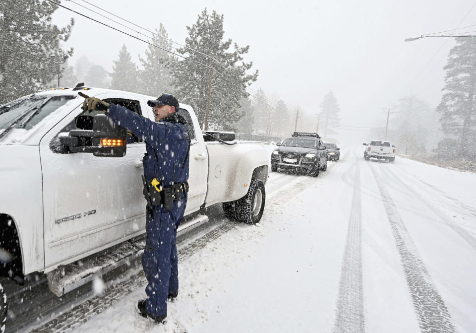 California Highway Patrol officer Mike Eshleman instructs a driver he may continue on Highway 2 in his 4-wheel drive vehicle as heavy snow falls near Wrightwood, Calif., on Dec. 12, 2022.  (Will Lester / The Orange County Register via AP)