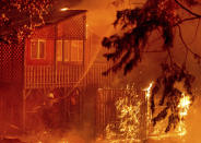 Firefighters work to save a home as the Dixie Fire tears through the Indian Falls community in Plumas County, Calif., on Saturday, July 24, 2021. The home, along with neighboring residences, ended up burning. (AP Photo/Noah Berger)