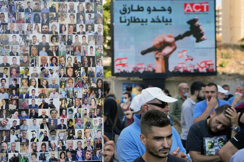 A man holds pictures of the victims who died in last year's massive blast at Beirut's seaport, during a protest in Beirut, Lebanon, Aug. 12, 2021. For eight months Tarek Bitar, a relatively obscure judge has quietly investigated one of the world's worst non-nuclear explosions with only two assistants helping him -- and a lot of powerful detractors blocking him. For many Lebanese Bitar is their only hope for truth and accountability in a country that craves both. But for the country's entrenched political class, the 47-year-old Bitar has become a nightmare that needs to be dealt with. The billboard in Arabic reads: "Only Tarek (Bitar) can take our revenge." (AP Photo/ Hassan Ammar)