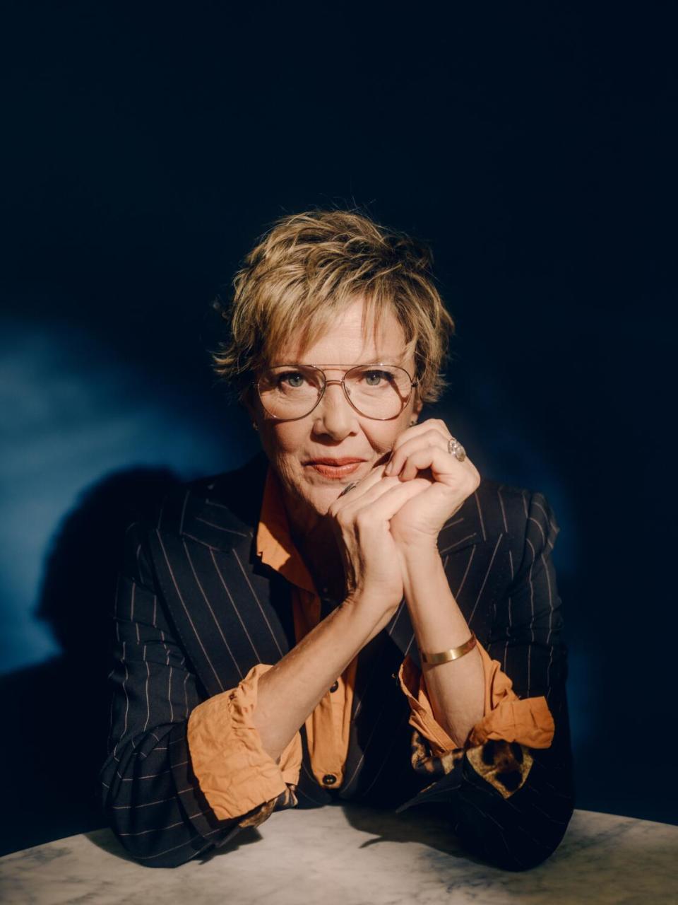 Annette Bening poses for a portrait with her chin resting on her hands.