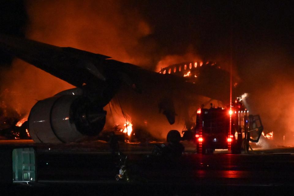 A fire engine is seen beside a Japan Airlines (JAL) passenger plane on the tarmac at Tokyo International Airport at Haneda on January 2, 2024. A Japan Airlines plane was in flames on the runway of Tokyo's Haneda Airport on January 2 after apparently colliding with a coast guard aircraft, television reports said.