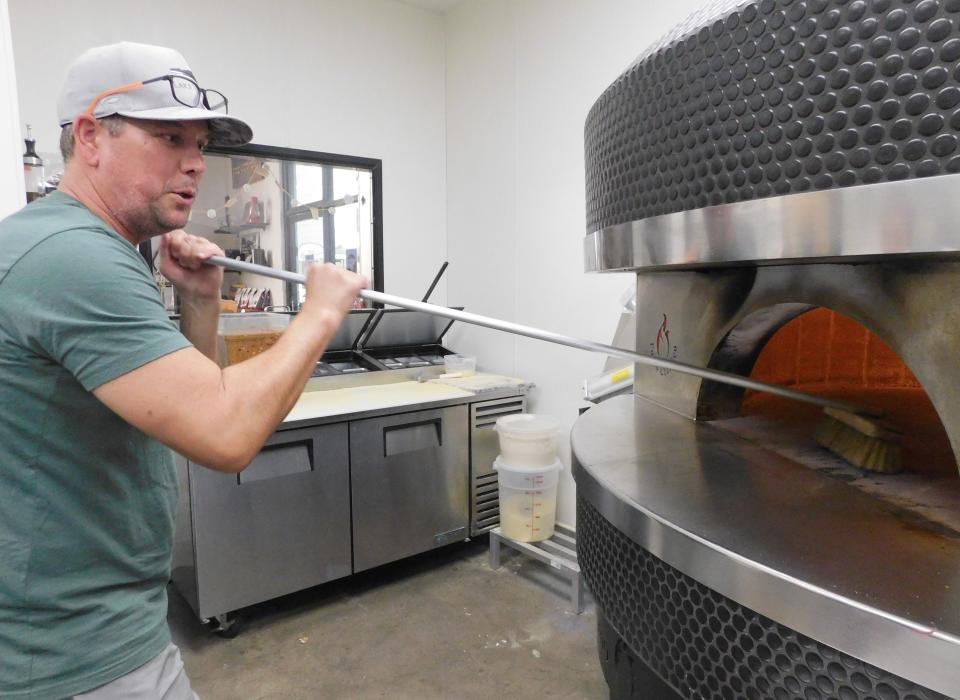 Nick Simpson, owner of new Moorpark restaurant The Outpost, sweeps the wood-fire pizza oven Thursday.