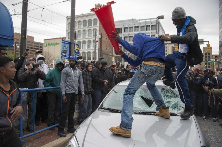 Demonstrators destroy the windshield of a Baltimore Police car on April 25, 2015 as they protest the death of Freddie Gray, an African American man who died of spinal cord injuries while in police custody