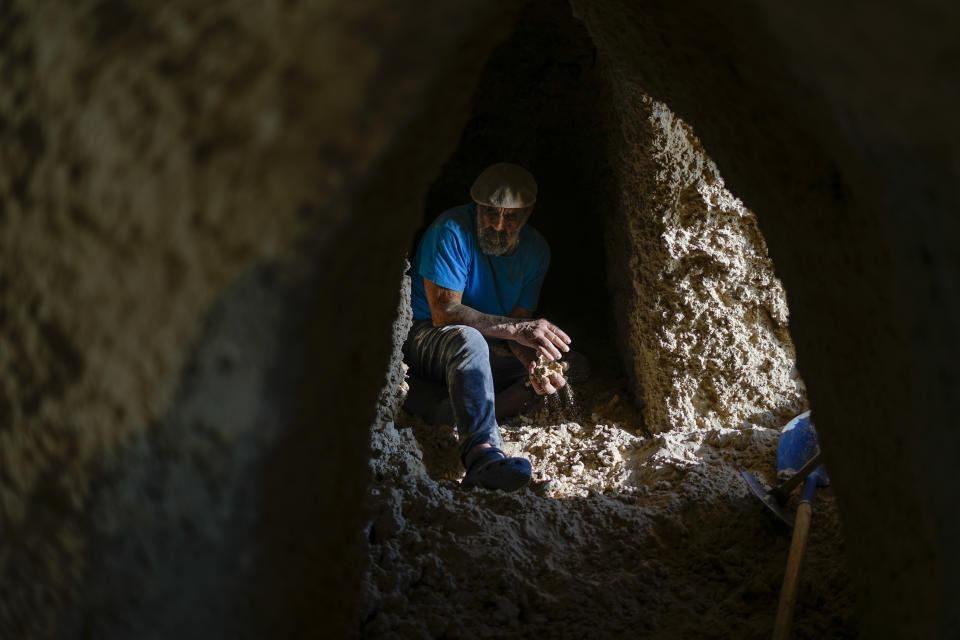 Nissim Kahlon works in a chamber in his home chiseled out of the sandstone cliffs overlooking the Mediterranean sea in Herzliya, Israel, Wednesday, June 28, 2023. Over half a century, Kahlon has transformed a tiny cave on a Mediterranean beach into an elaborate underground labyrinth filled with chiseled tunnels, detailed mosaic floors and a network of staircases and mysterious chambers. Fifty years after Kahlon moved into the home, Israel's Environmental Protection Agency has served him an eviction notice, claiming the structure threatens Israel's coastline. (AP Photo/Ariel Schalit)