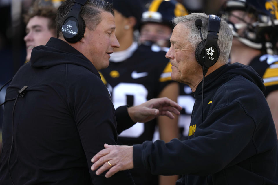 Iowa head coach Kirk Ferentz talks with his son offensive coordinator Brian Ferentz, left, before an NCAA college football game against Illinois, Saturday, Nov. 18, 2023, in Iowa City, Iowa. (AP Photo/Charlie Neibergall)