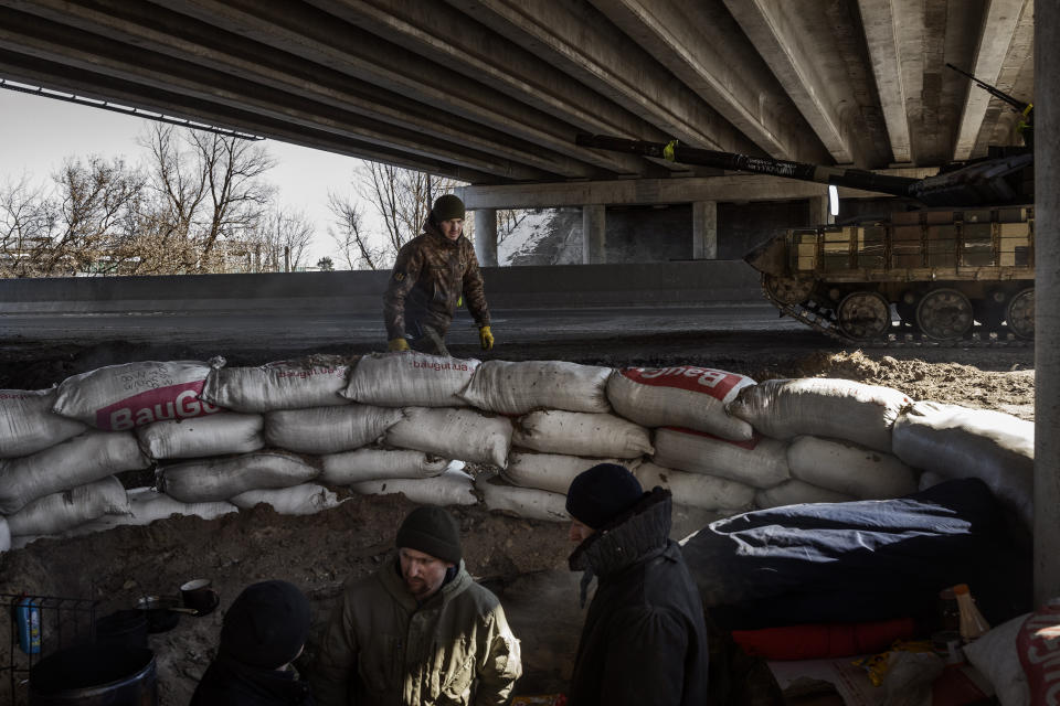 Ukrainian soldiers rest at a checkpoint on the road to Kyiv's eastern front