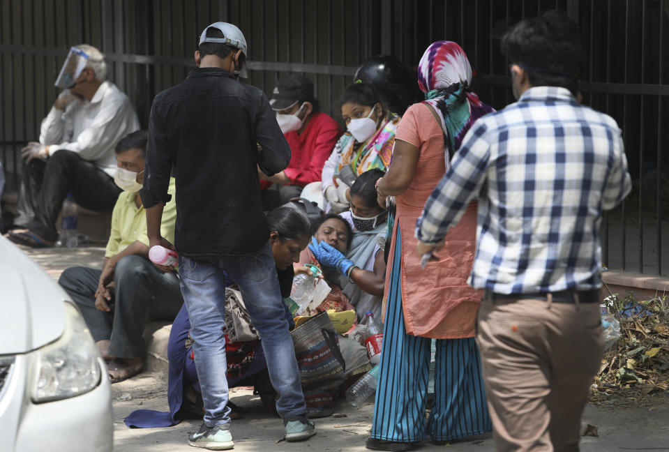 A woman comforts her relative as they wait to receive the body of a person who died of COVID-19 outside a mortuary, in New Delhi, India, Monday, April 19, 2021. New Delhi imposed a weeklong lockdown Monday night to prevent the collapse of the Indian capital's health system, which authorities said had been pushed to its limit amid an explosive surge in coronavirus cases. (AP Photo/Manish Swarup)