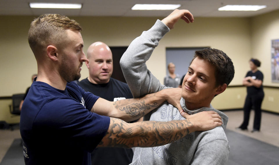 In this photo taken Sept. 10, 2019, Ryan Russo, left, and Mike Herrall go through a drill as instructor Sean Fuller looks on during a defensive tactic training class at the American Medical Response training center in Clackamas, Ore. Paramedics in Portland are undergoing mandatory training in defensive tactics after a rash of high-profile attacks against them as they respond to 911 calls for people in a mental health or drug-related crisis. (AP Photo/Steve Dykes)