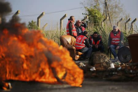 Striking French CGT labour union employees sit near a barricade to block the entrance of the fuel depot of the SFDM company near the oil refinery of Donges, France, May 25, 2016 in protest over proposed new labour laws. REUTERS/Stephane Mahe