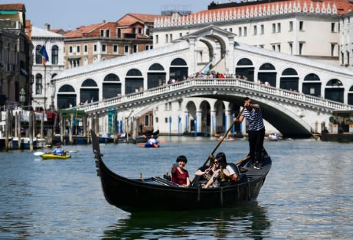 A gondolier rows tourists along the Grand Canal in Venice, a more traditional sight than the massive cruise ships which now visit the historic city