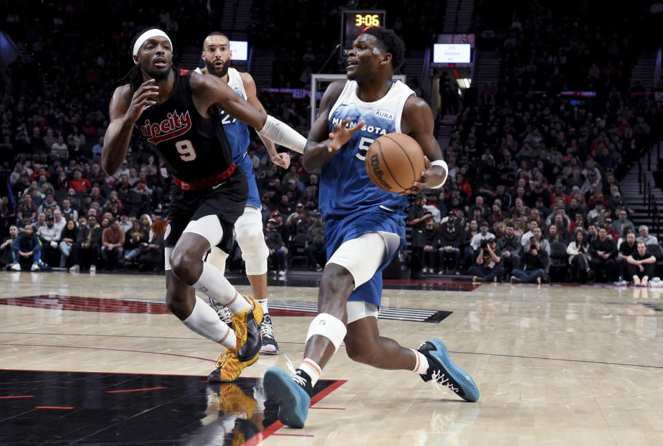 Minnesota Timberwolves guard Anthony Edwards, right, drives to the basket against Portland Trail Blazers forward Jerami Grant during the first half of an NBA basketball game in Portland, Ore., Thursday Feb. 15, 2024. (AP Photo/Steve Dykes)