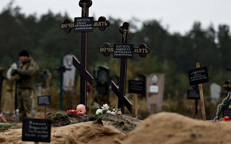 A doll is seen among graves which Ukrainian officials say is a civilian mass grave, in the newly recaptured town of Lyman - Zohra Bensemra/Reuters