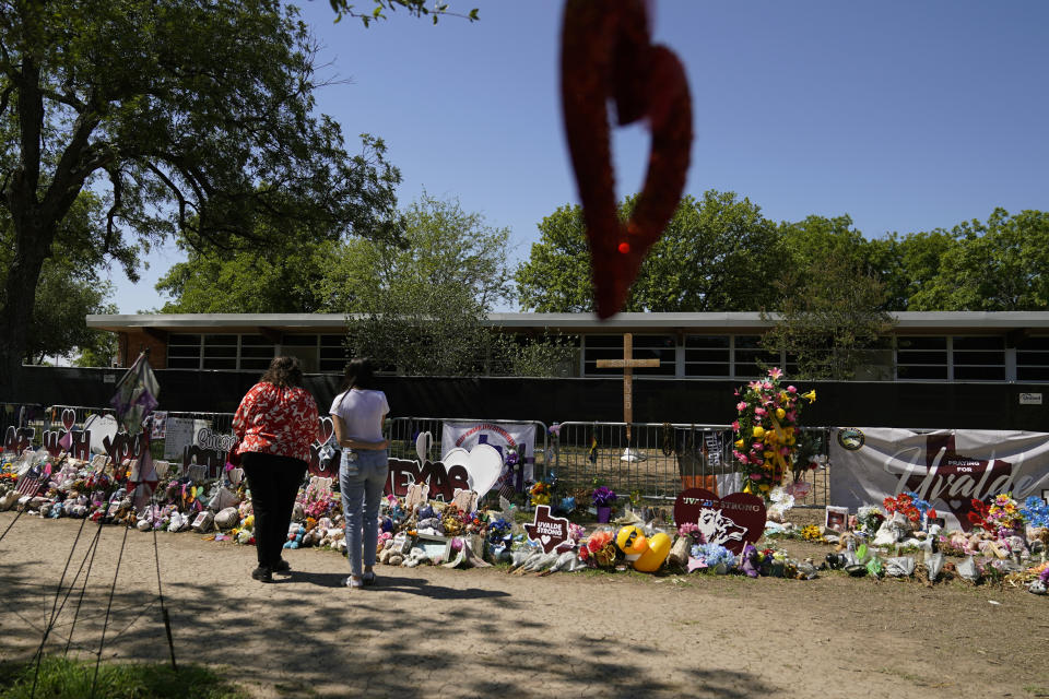 Maria Elena Jasso, a teacher from San Antonio, left, visits a make-shift memorial honoring the victims of the school shootings at Robb Elementary, Monday, July 11, 2022, in Uvalde, Texas. (AP Photo/Eric Gay)