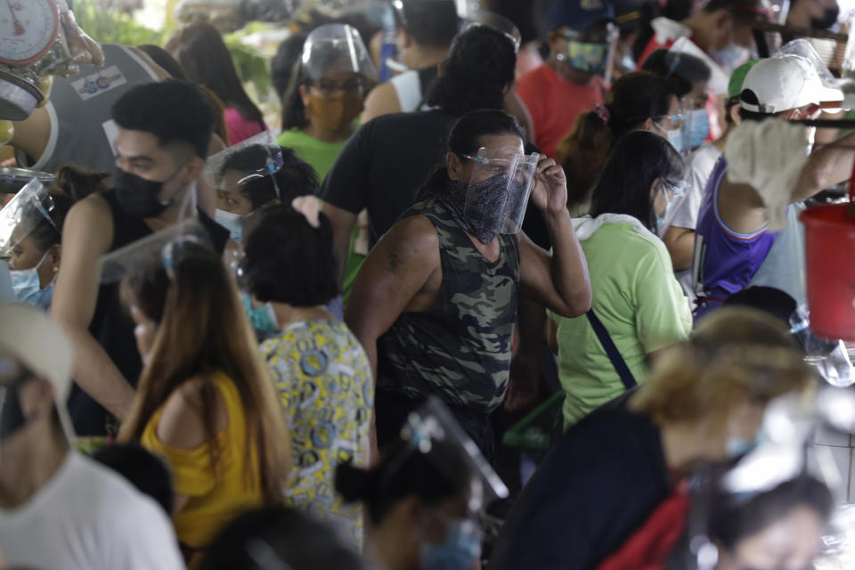 A man arranges his face shield to prevent the spread of the coronavirus at the Munoz market in Quezon city, Philippines as they prepare for a stricter lockdown on Sunday March 28, 2021. The government will start stricter lockdown measures next week as the country struggles to control an alarming surge in COVID-19 cases. (AP Photo/Aaron Favila)