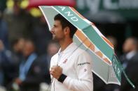 Tennis - French Open - Roland Garros - Novak Djokovic of Serbia v Roberto Bautista Agut of Spain - Paris, France - 31/05/16. Djokovic holds an umbrella as he arrives on the court. REUTERS/Gonzalo Fuentes