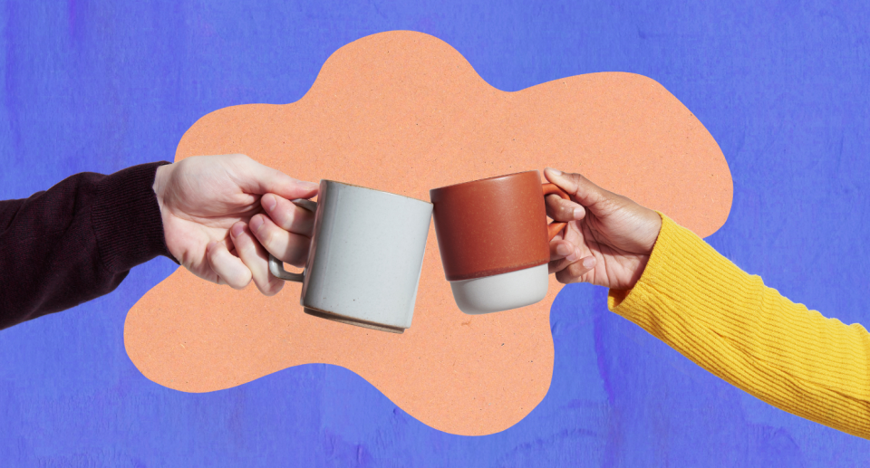 two people wearing sweaters holding coffee cups cheering each other 