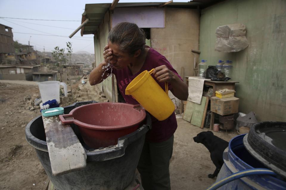 Maria Jimenez lava su cara con agua afuera de su casa en el barrio de Nueva Esperanza en Lima, Perú, el jueves 21 de marzo de 2019. (AP Foto/Martin Mejia)