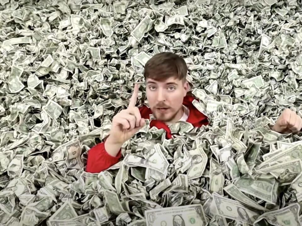 A picture of MrBeast sitting in a pile of cash.