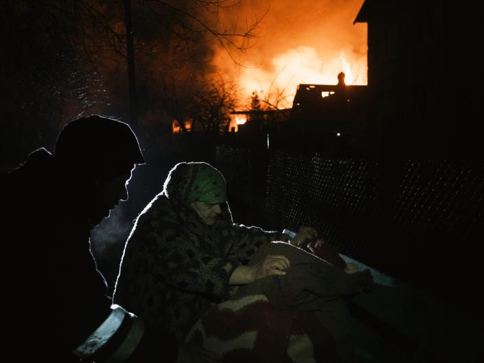 A local woman collects things near a burning building (EPA)