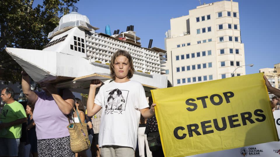 A young person holds a placard which reads as "Stop cruises" during the demonstration on Sunday, July 21. - Jaime Reina/AFP/Getty Images