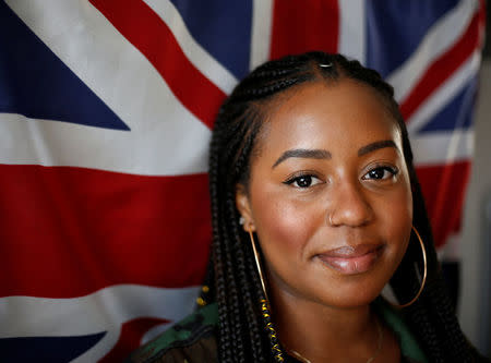 Ishea Brown, who plans to hold a Royal wedding viewing party with 19 of her friends, complete with fascinators and Hennessy, poses for a portrait in front of a UK flag at her apartment in Seattle, Washington, U.S., May 14, 2018. Picture taken May 14, 2018. REUTERS/Lindsey Wasson