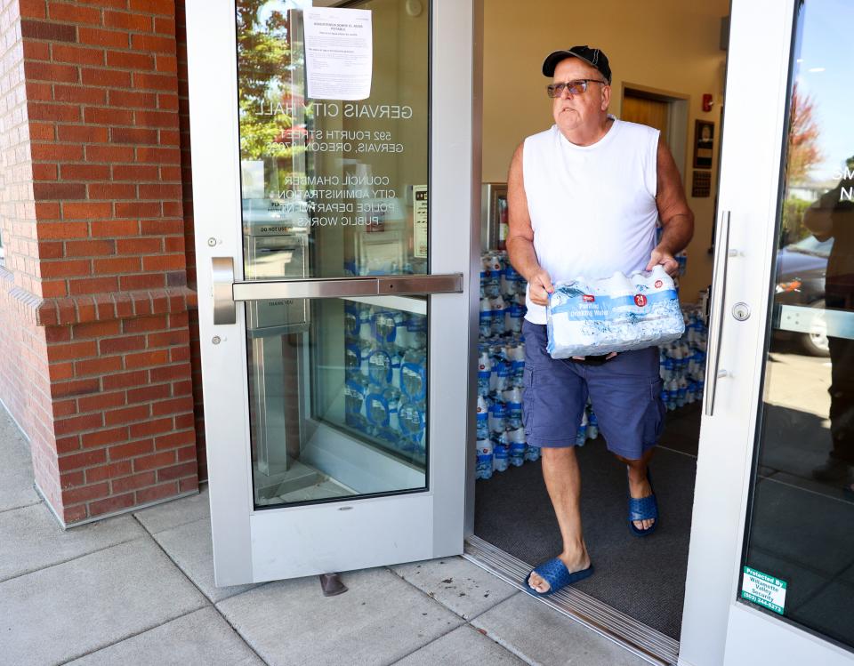 Keith Gilland, husband of Gervais Mayor Annie Gilland, helps pass out water to residents Tuesday.