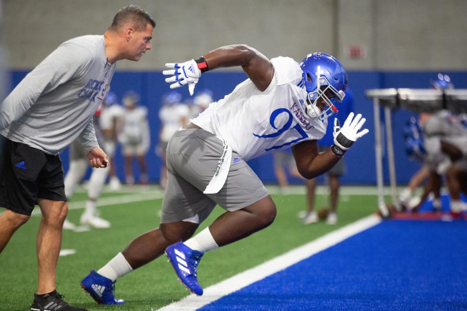 Kansas junior defensive lineman Kenean Caldwell (97) takes off at the command of defensive tackles coach Jim Panagos during practice one evening during fall camp this year at the indoor practice facility in Lawrence.