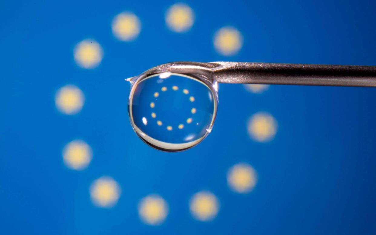 A drop of vaccine from a syringe with the EU flag in the background - reuters/dado ruvic