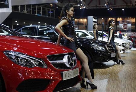 Models stand beside the Mercedes E250 Coupe during the 21st Indonesia International Motor Show (IIMS) in Jakarta, September 23, 2013. REUTERS/Beawiharta