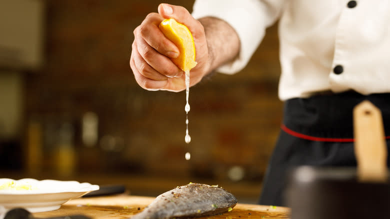 Chef squeezing lemon over fish 