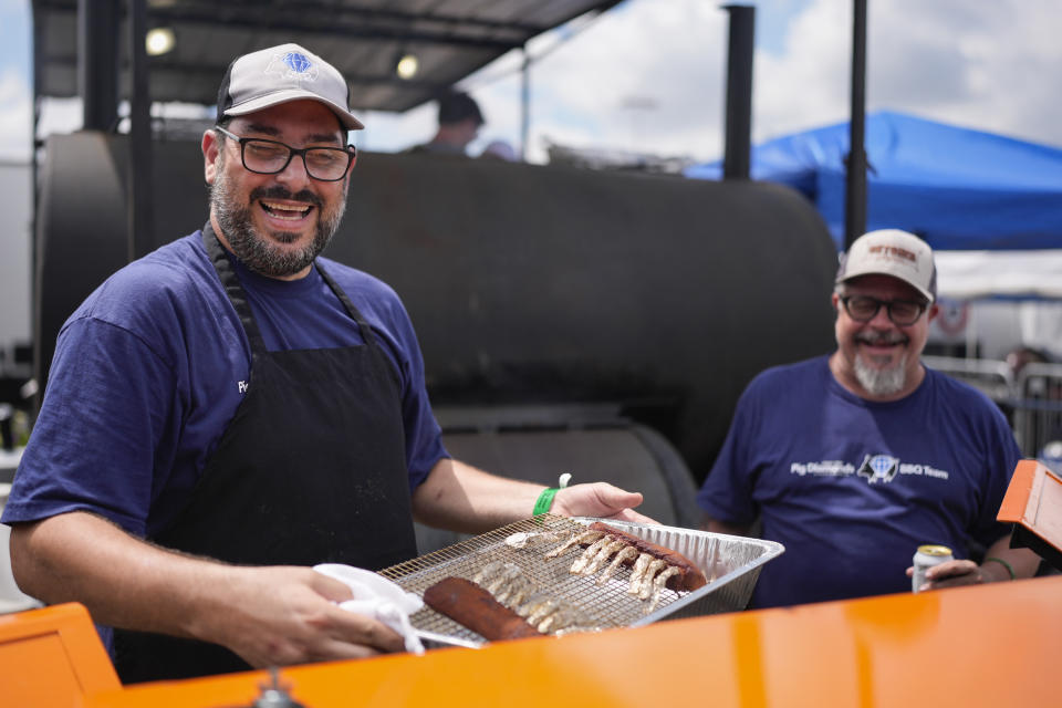 Adriano Pedro, left, and Bruno Panhoca of Brazil smile as they pull lamb from the grill at the World Championship Barbecue Cooking Contest, Friday, May 17, 2024, in Memphis, Tenn. The two are members of the Pig Diamonds team that includes members from the United States and Brazil. (AP Photo/George Walker IV)