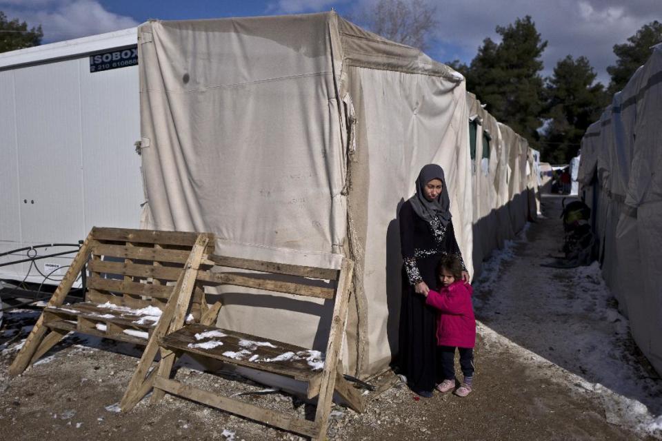 In this Monday, Jan. 9, 2017 photo, Rania Askar, 31, a Syrian refugee from from Deir el-Zour, who lost her child in her 6th month of pregnancy, poses for a picture while holding her daughter Maya, 4, outside her shelter at the refugee camp of Ritsona, Greece. "I didn't know that there was something wrong with my pregnancy until the day I woke up bleeding, I am so sad my heart is broken, this wouldn't happen if I was surrounded by my sisters in Germany." Askar said. Squalid conditions and subfreezing temperatures in Greece’s migrant camps this winter are taking their toll on everyone living in them with expectant mothers and babies especially feel the brunt. (AP Photo/Muhammed Muheisen)