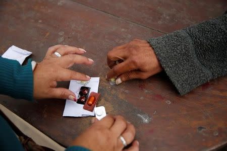 Orlando Lajo,54, receives medicine for multidrug-resistant tuberculosis from health worker Gladys Trujillo from organisation Partners in Health, at a homeless shelter in Carabayllo in Lima, Peru July 14, 2016. REUTERS/Mariana Bazo