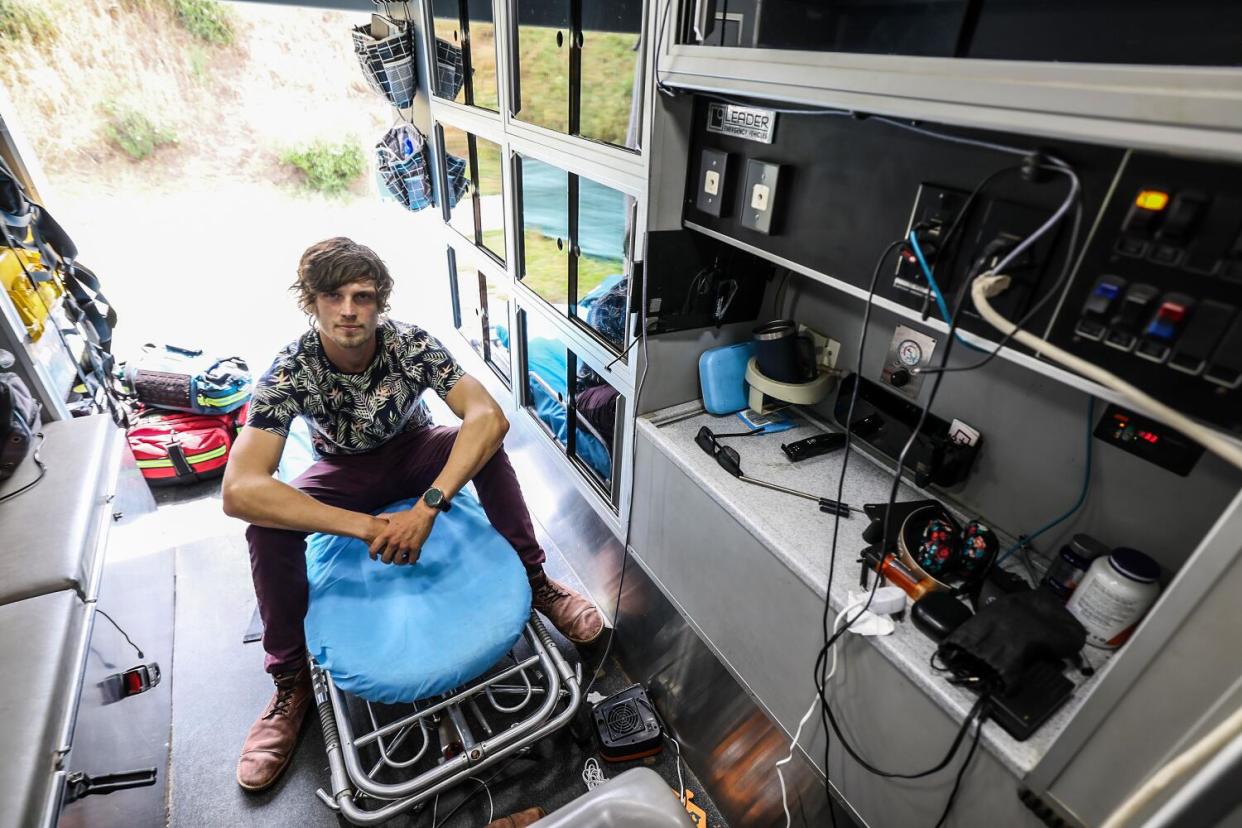 A man sits on a gurney inside an ambulance.