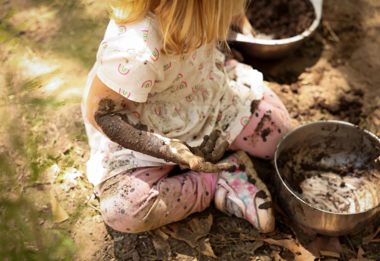 A little girl plays in the mud.