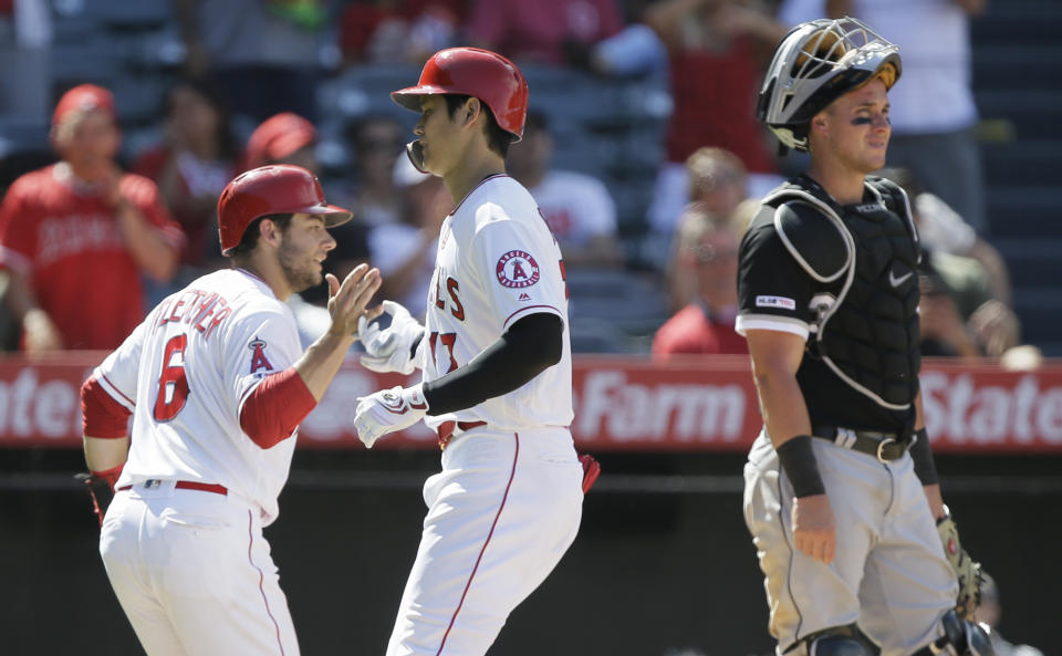 Los Angeles Angels' David Fletcher, left, congratulates designated hitter Shohei Ohtani, center, after Ohtani hit a two-run home run, with Chicago White Sox catcher James McCann, right, looking away during the seventh inning of a baseball game in Anaheim, Calif., Sunday, Aug. 18, 2019. (AP Photo/Alex Gallardo)