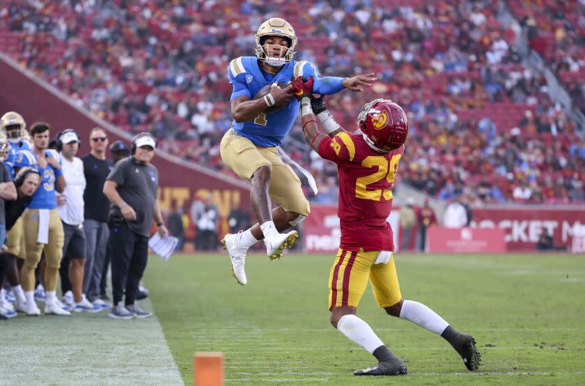 UCLA quarterback Dorian Thompson-Robinson, left, leaps in attempt to get past USC safety Xavion Alford