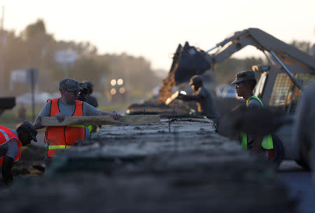 Members of the National Guard work on a long sand bag flood barrier being built by the South Carolina Department of Transportation on U.S. 501 to lesson damage to roads anticipated from floods caused by Hurricane Florence, now downgraded to a tropical depression, in Conway, South Carolina, U.S. September 19, 2018. REUTERS/Randall Hill