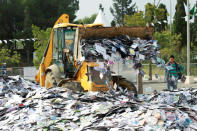 <p>A crane destroys more than a million pirated music, movie and software CDs and DVDs in a government campaign against piracy in Algiers on May 23, 2016. (Ramzi Boudina/Reuters) </p>