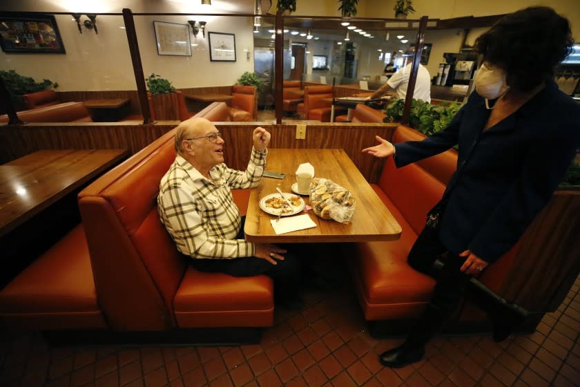 LOS ANGELES, CA - MARCH 15: Phillip Guttman gets a gift of freshly baked cookies from third generation owner Jacqueline Canter as he eats breakfast inside Canter's Delicatessen in Fairfax Village of Los Angeles Monday morning as L.A. County is reopening by permitting various businesses to reopen at a portion of their capacity. Phillip has been coming to Canter's Deli since it opened in the 1950's. Restaurants can open indoors at 25% capacity but must maintain eight feet of distance between tables. Indoor malls can operate at 50% capacity. Museums, zoos and aquariums may open indoors at 25% capacity; gyms, fitness centers and yoga and dance studios at 10% capacity; movie theaters at 25% capacity, with reserved, separated seating for groups; and retail and personal care services at 50% capacity. Canter's Faifax on Monday, March 15, 2021 in Los Angeles, CA. (Al Seib / Los Angeles Times).