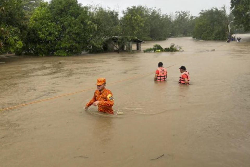 In this photo provided by the Philippine Coast Guard, rescuers wade along floodwaters caused by Typhoon Doksuri as they search for residents to evacuate to higher grounds in Bacarra, Ilocos Norte province, northern Philippines on Wednesday July 26, 2023. Typhoon Doksuri ripped off tin roofs from homes, engulfed low-lying villages in flood, knocked down power and displaced more than 12,000 people Wednesday as it smashed into a small island and lashed northern Philippine provinces overnight with ferocious wind and rain, officials said. (Philippine Coast Guard via AP)