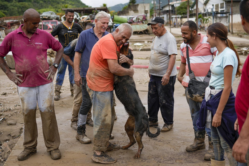 A man reunites with his dog, rescued by neighbors from the mud, after flooding caused by intense rains in Las Tejerias, Venezuela, Sunday, Oct. 9, 2022, after (AP Photo/Matias Delacroix)