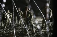 Agentes de la Patrulla Fronteriza de Estados Unidos permanecen de guardia en el lado estadounidense de la frontera con México, vistos a través del alambre de concertina desde Tijuana, México, donde la línea fronteriza se encuentra con el Océano Pacífico, el jueves 15 de noviembre de 2018. (AP Foto/Marco Ugarte)