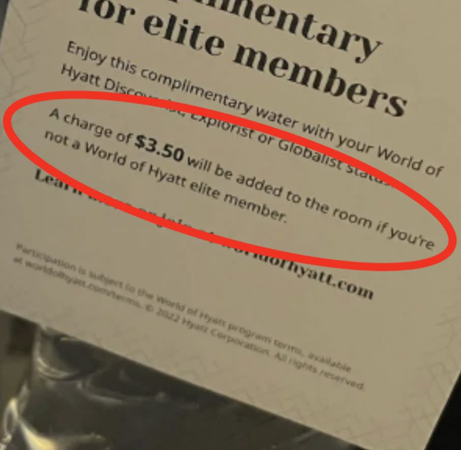 A water bottle with a tag that reads, "Complimentary for elite members. A charge of $5.50 will be added to the room if you're not a World of Hyatt elite member."