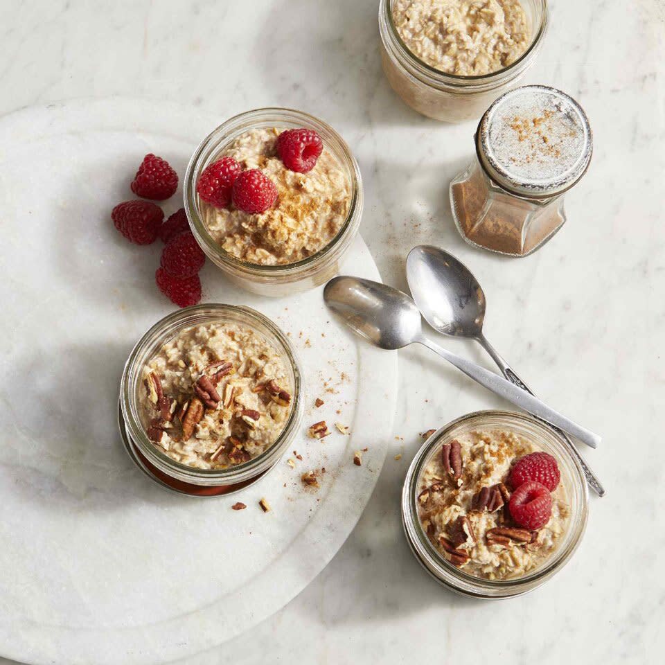 cinnamon roll overnight oats shot overhead in mason jars with raspberries and pecans on top